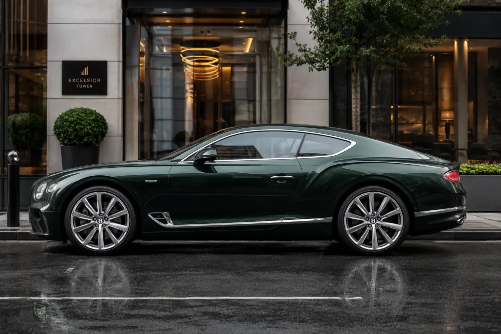 A side profile of a Bentley fitted with elegant high end rims, parked in a modern urban setting